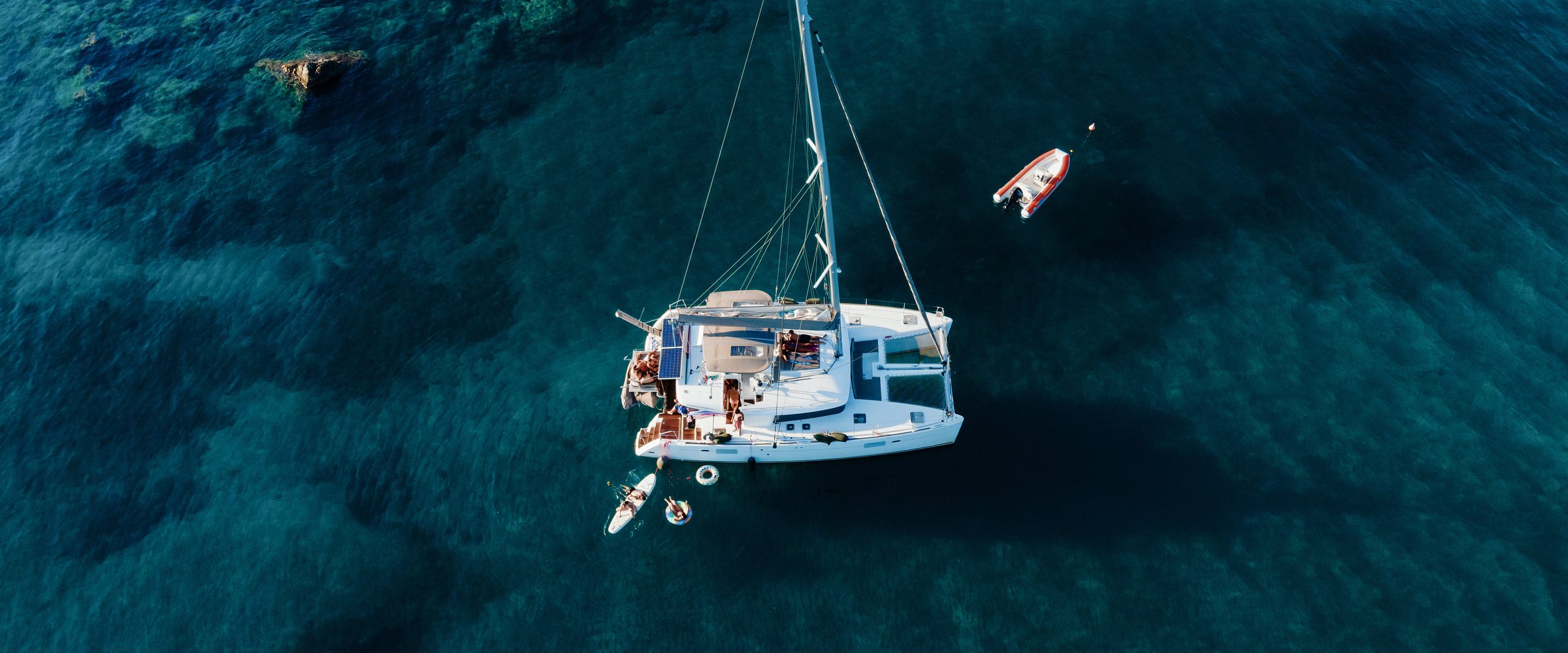 Amazing top view of Catamaran anchored in blue sea in summer. Travel background. Cruise vacation.