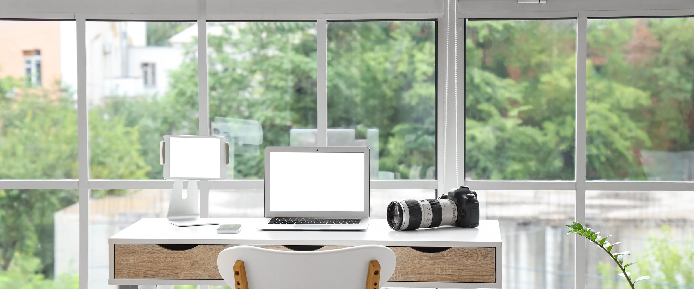 Laptop with tablet computer and camera on photographer's desk in office