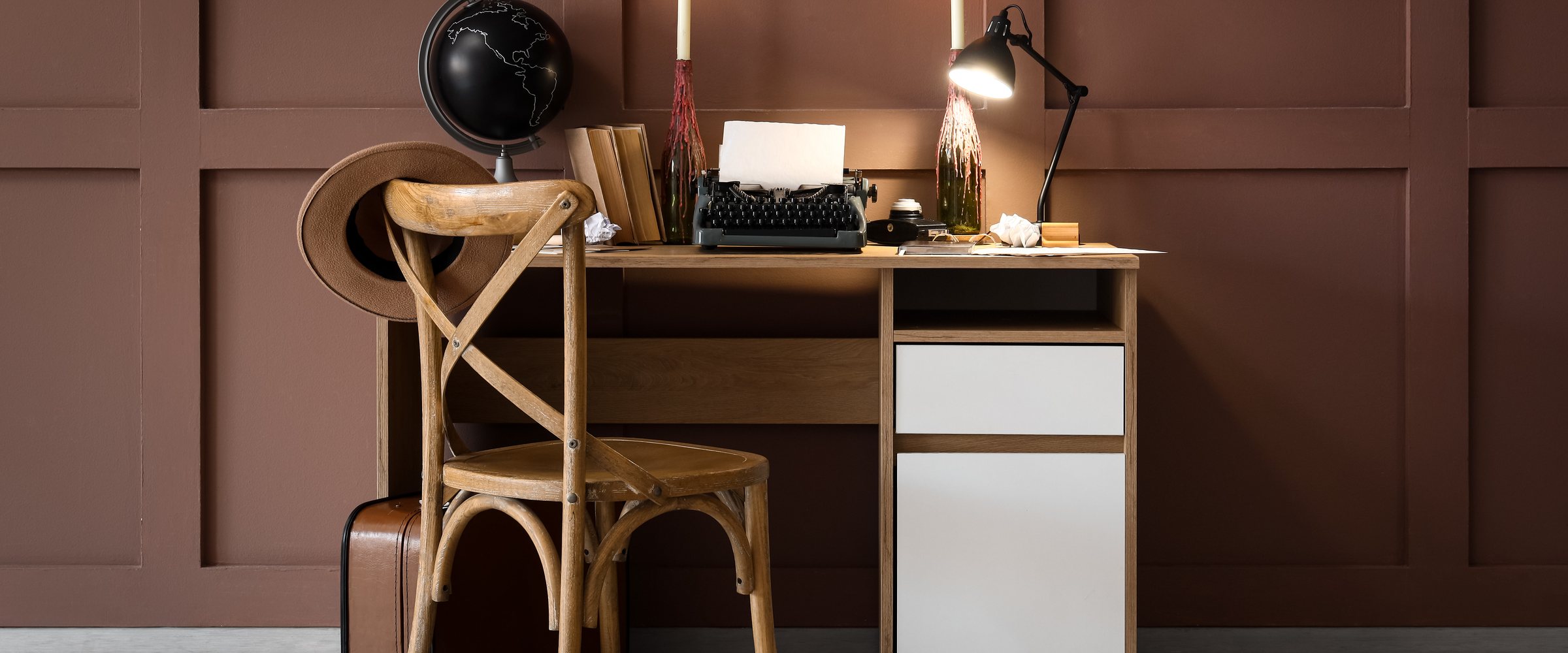 Vintage writers desk with typewriter, globe, and candles in a cozy home office setting