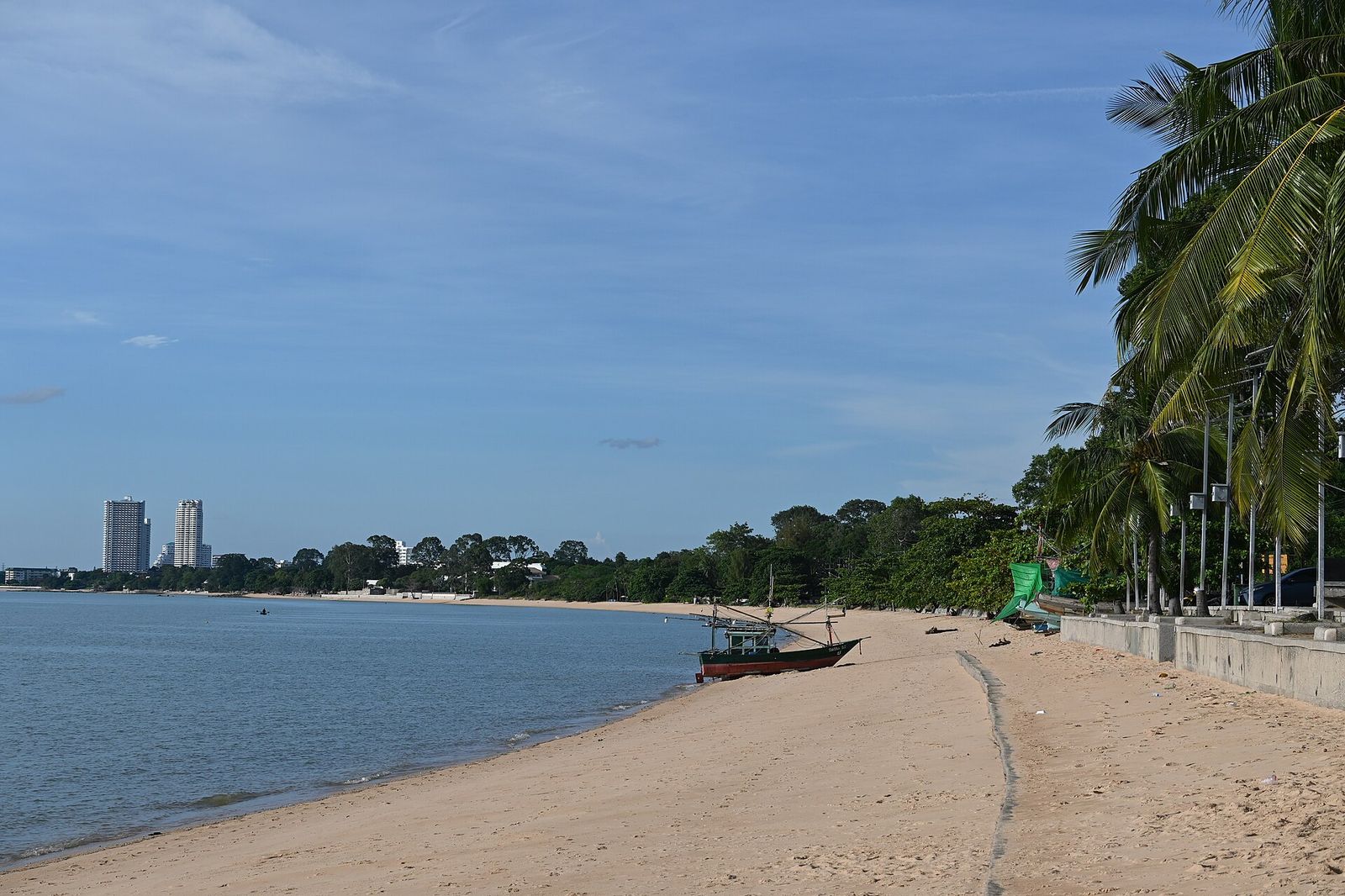 The photo shows a beautiful tropical beach scene with a stretch of light sandy shoreline curving along calm blue waters, Palm Beach International Boat Show